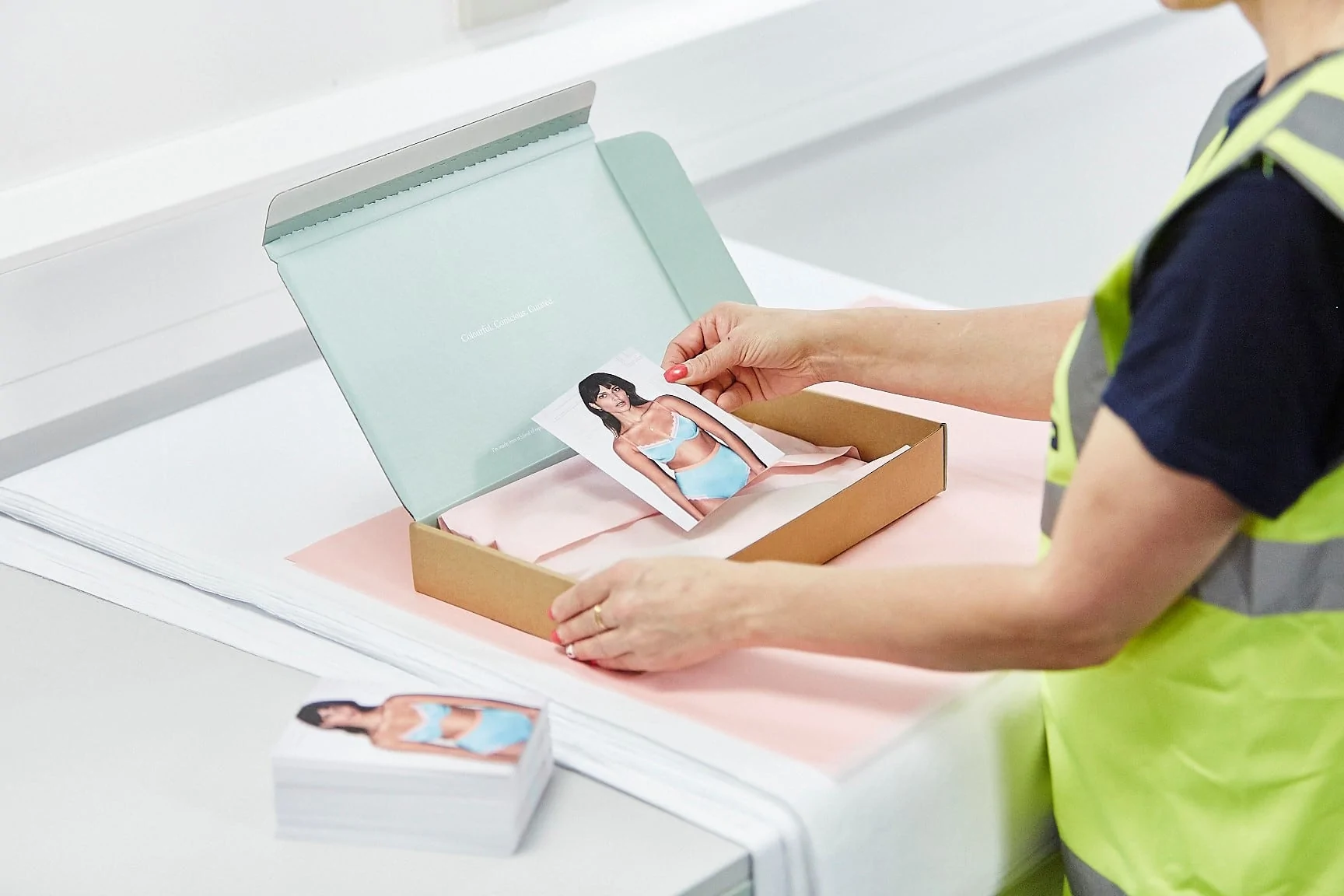 Warehouse employee packing fashion postcard into a rectangular box