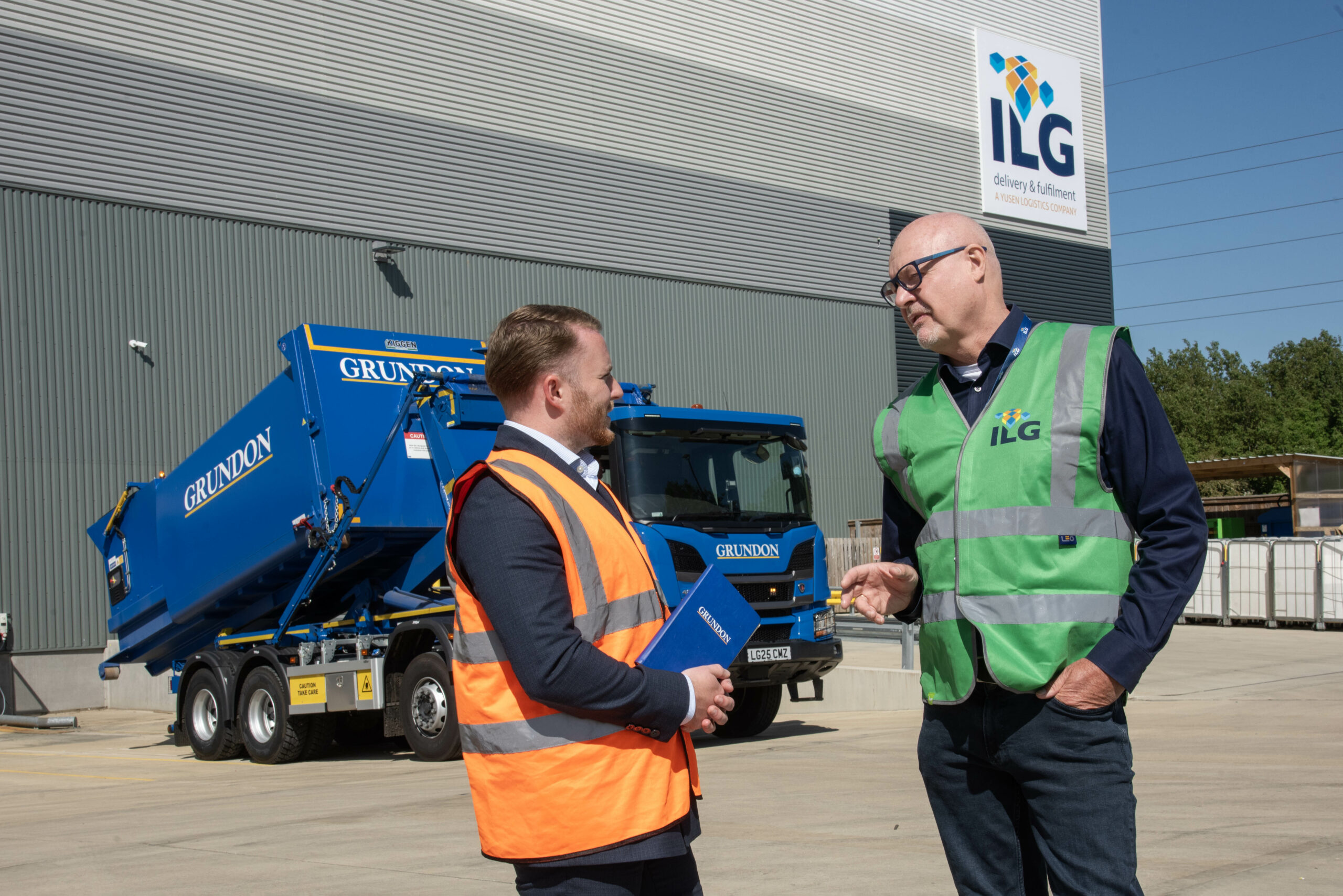Two men talking to each other in front of a Grundons truck