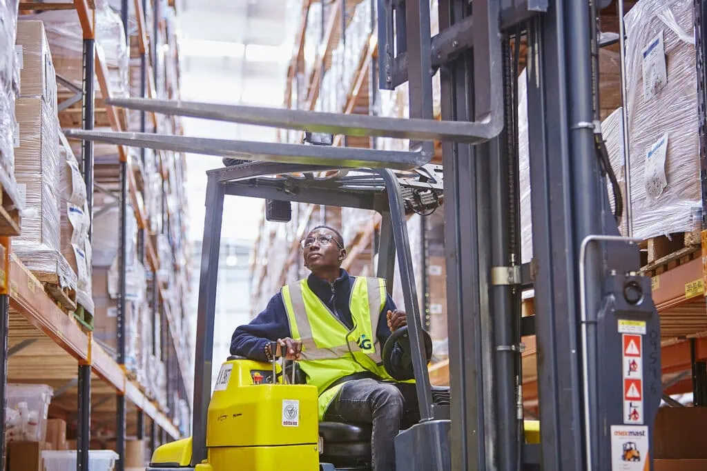 man on forklift looking at stock on shelves