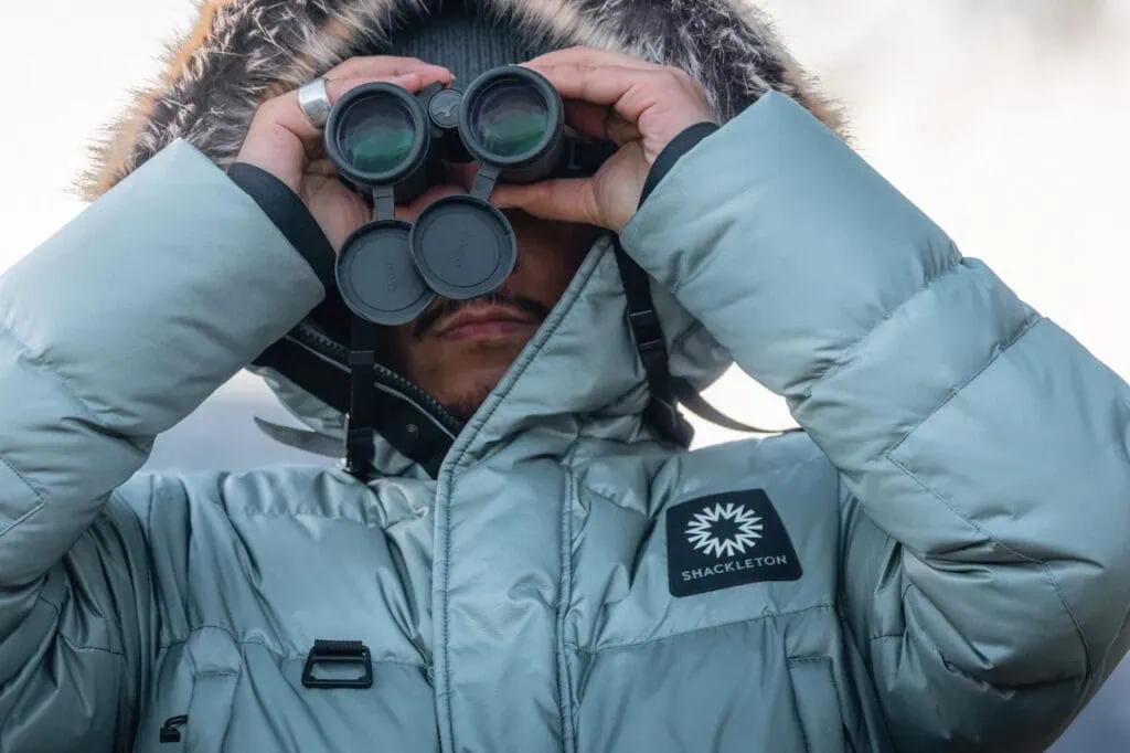 Man looking through binoculars wearing Shackleton coat